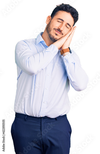 Young hispanic man wearing business clothes sleeping tired dreaming and posing with hands together while smiling with closed eyes.