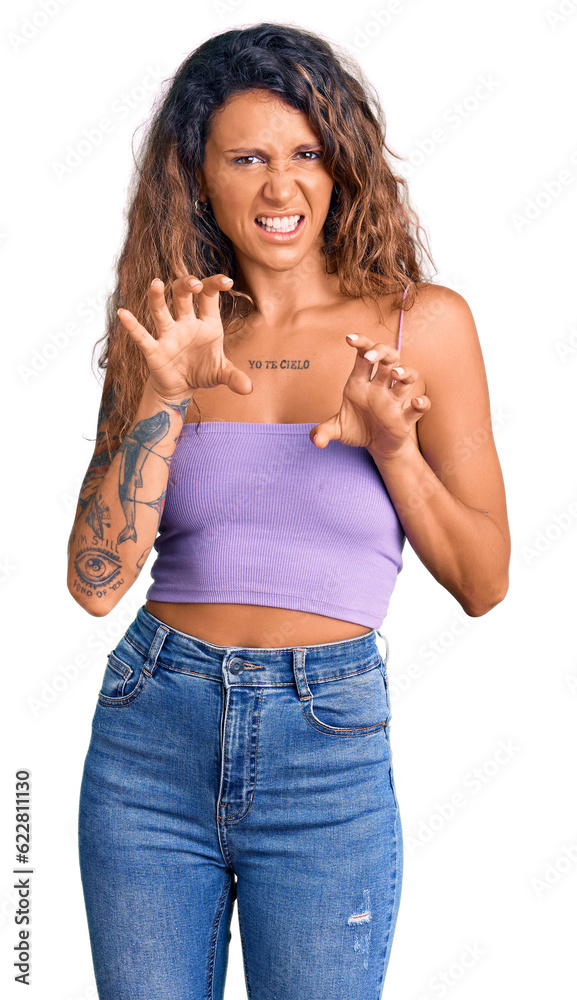 Young hispanic woman with tattoo wearing casual clothes smiling funny doing claw gesture as cat, aggressive and sexy expression Young hispanic woman with tattoo wearing casual clothes smiling funny doing claw gesture as cat, aggressive and sexy expression