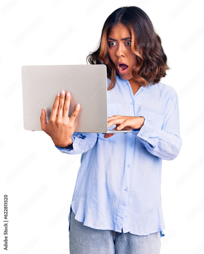 Young beautiful mixed race woman working using computer laptop scared and amazed with open mouth for surprise, disbelief face Young beautiful mixed race woman working using computer laptop scared and amazed with open mouth for surprise, disbelief face