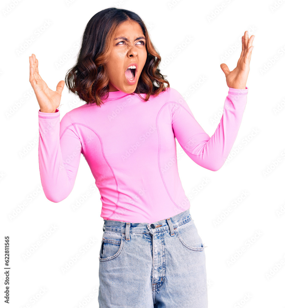 Young beautiful mixed race woman wearing pink shirt crazy and mad shouting and yelling with aggressive expression and arms raised. frustration concept. Young beautiful mixed race woman wearing pink shirt crazy and mad shouting and yelling with aggressive expression and arms raised. frustration concept.
