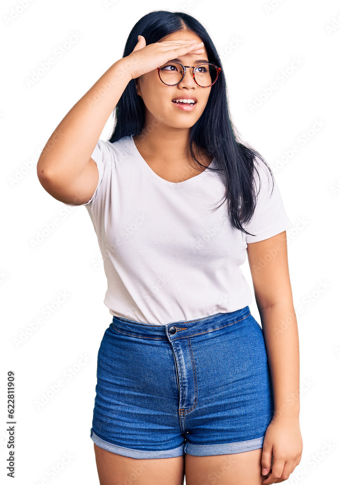 Young beautiful asian girl wearing casual clothes and glasses very happy and smiling looking far away with hand over head. searching concept.