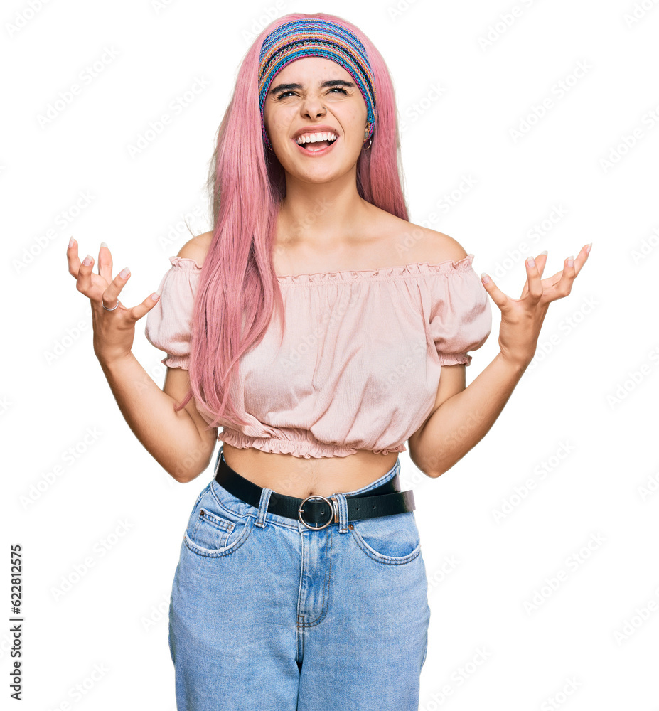 Young hispanic girl with pink hair crazy and mad shouting and yelling with aggressive expression and arms raised. frustration concept. Young hispanic girl with pink hair crazy and mad shouting and yelling with aggressive expression and arms raised. frustration concept.