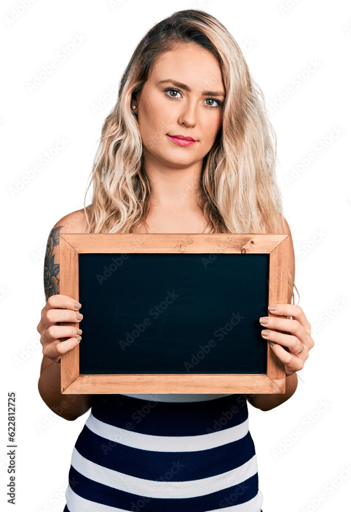 Young blonde woman holding blackboard relaxed with serious expression on face. simple and natural looking at the camera. Young blonde woman holding blackboard relaxed with serious expression on face. simple and natural looking at the camera.