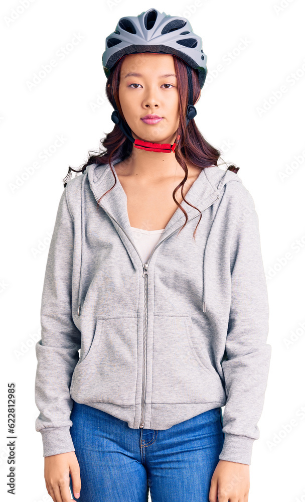 Young beautiful chinese girl wearing bike helmet with serious expression on face. simple and natural looking at the camera. Young beautiful chinese girl wearing bike helmet with serious expression on face. simple and natural looking at the camera.