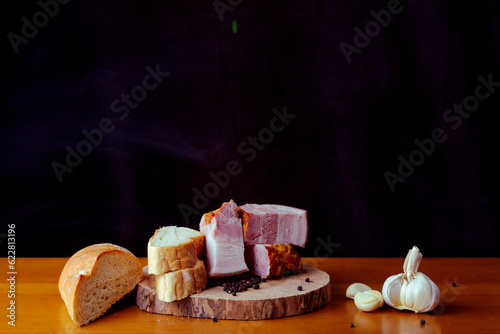 Bacon with meat with knife on the wooden cutting board with black background