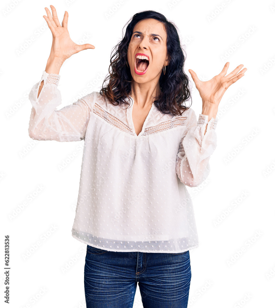 Young beautiful hispanic woman wearing casual clothes crazy and mad shouting and yelling with aggressive expression and arms raised. frustration concept. Young beautiful hispanic woman wearing casual clothes crazy and mad shouting and yelling with aggressive expression and arms raised. frustration concept.