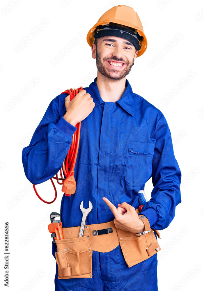Young hispanic man wearing elecrician uniform holding cable smiling happy pointing with hand and finger