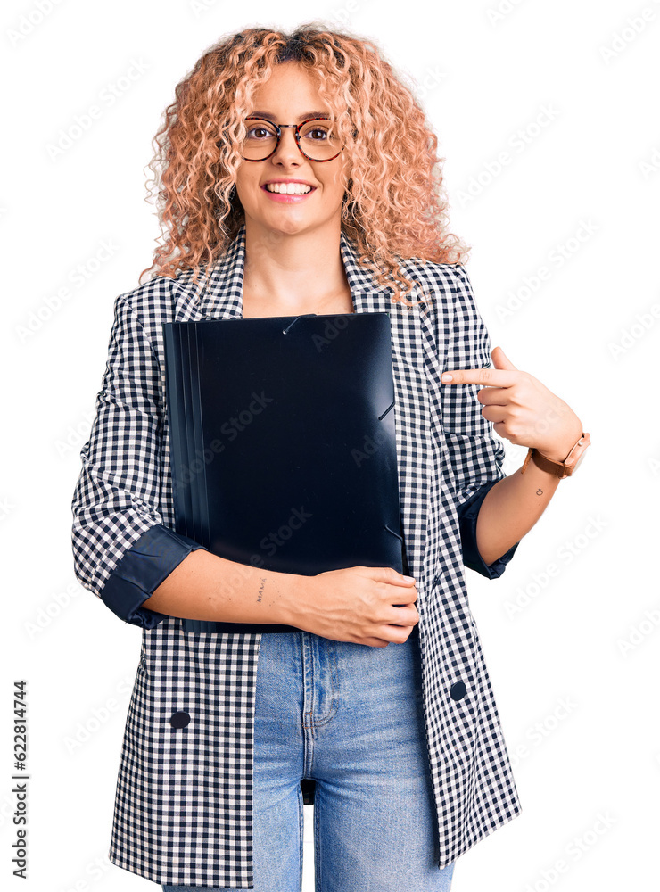 Young blonde woman with curly hair holding business folder smiling happy pointing with hand and finger Young blonde woman with curly hair holding business folder smiling happy pointing with hand and finger