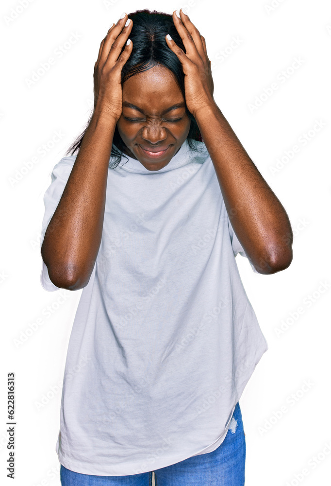 Young african american woman wearing casual white t shirt suffering from headache desperate and stressed because pain and migraine. hands on head. Young african american woman wearing casual white t shirt suffering from headache desperate and stressed because pain and migraine. hands on head.