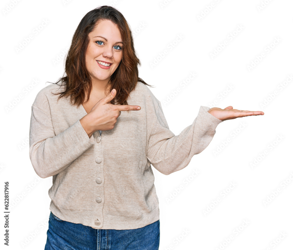 Young plus size woman wearing casual clothes amazed and smiling to the camera while presenting with hand and pointing with finger. Young plus size woman wearing casual clothes amazed and smiling to the camera while presenting with hand and pointing with finger.