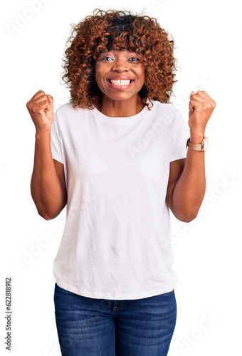 Young african american woman wearing casual white tshirt celebrating surprised and amazed for success with arms raised and open eyes. winner concept.