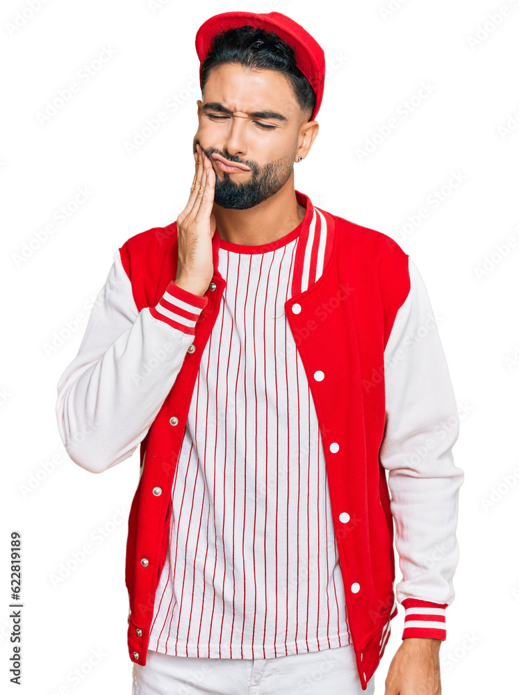 Young man with beard wearing baseball uniform touching mouth with hand with painful expression because of toothache or dental illness on teeth. dentist Young man with beard wearing baseball uniform touching mouth with hand with painful expression because of toothache or dental illness on teeth. dentist