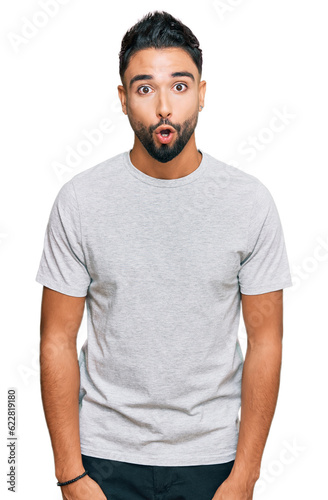 Young man with beard wearing casual grey tshirt afraid and shocked with surprise expression, fear and excited face.