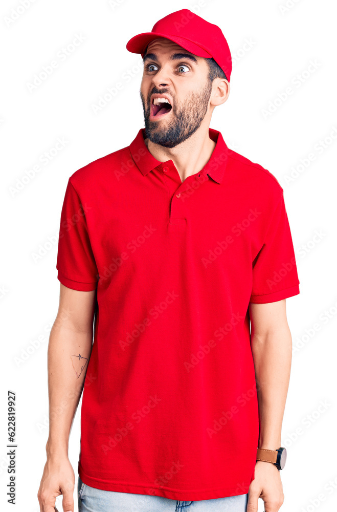 Young handsome man with beard wearing delivery uniform angry and mad screaming frustrated and furious, shouting with anger. rage and aggressive concept. Young handsome man with beard wearing delivery uniform angry and mad screaming frustrated and furious, shouting with anger. rage and aggressive concept.
