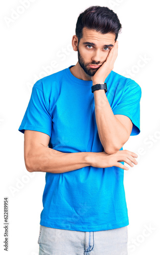 Young handsome man with beard wearing casual t-shirt thinking looking tired and bored with depression problems with crossed arms.