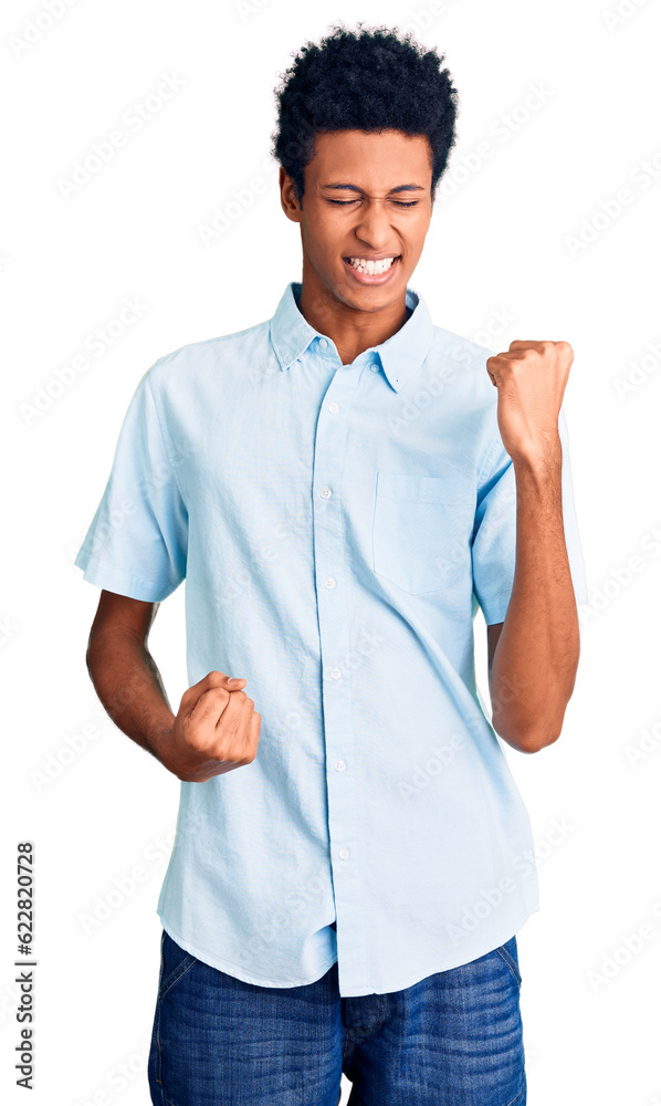 Young african american man wearing casual clothes celebrating surprised and amazed for success with arms raised and eyes closed. winner concept. Young african american man wearing casual clothes celebrating surprised and amazed for success with arms raised and eyes closed. winner concept.