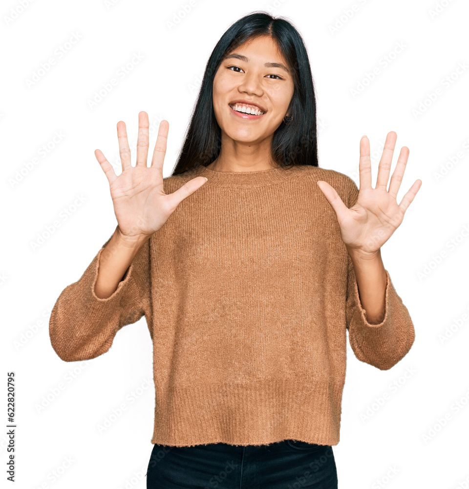 Beautiful young asian woman wearing casual winter sweater showing and pointing up with fingers number ten while smiling confident and happy. Beautiful young asian woman wearing casual winter sweater showing and pointing up with fingers number ten while smiling confident and happy.