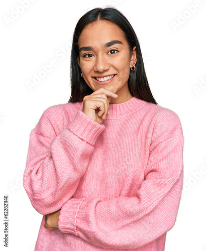 Young asian woman wearing casual winter sweater looking confident at the camera smiling with crossed arms and hand raised on chin. thinking positive.
