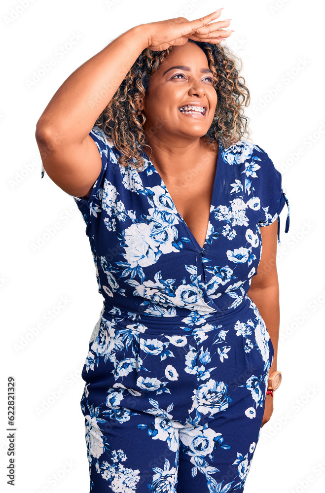 Young african american plus size woman wearing casual clothes very happy and smiling looking far away with hand over head. searching concept.