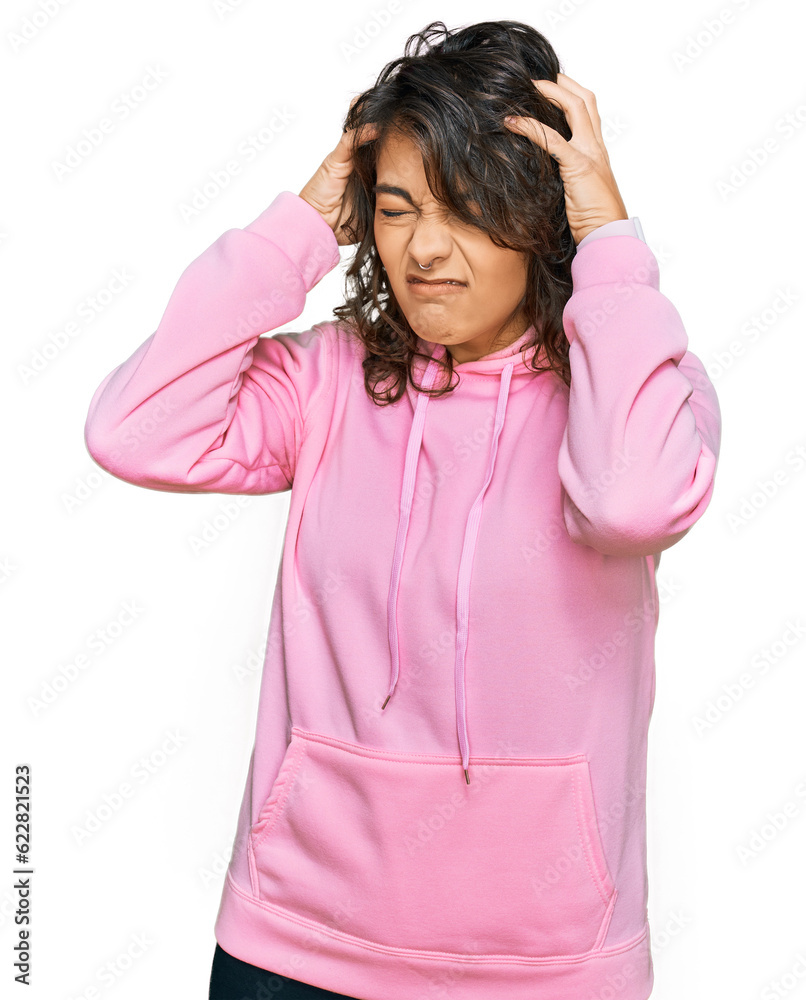 Young hispanic woman wearing casual sweatshirt suffering from headache desperate and stressed because pain and migraine. hands on head. Young hispanic woman wearing casual sweatshirt suffering from headache desperate and stressed because pain and migraine. hands on head.