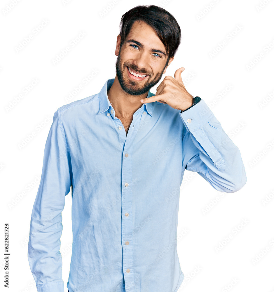 Hispanic man with blue eyes wearing business shirt smiling doing phone gesture with hand and fingers like talking on the telephone. communicating concepts. Hispanic man with blue eyes wearing business shirt smiling doing phone gesture with hand and fingers like talking on the telephone. communicating concepts.