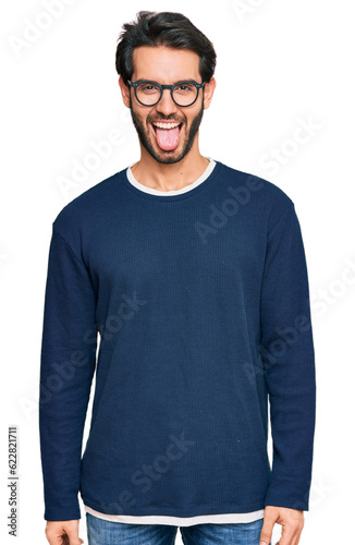 Young hispanic man wearing casual clothes and glasses sticking tongue out happy with funny expression. emotion concept. © Krakenimages.com