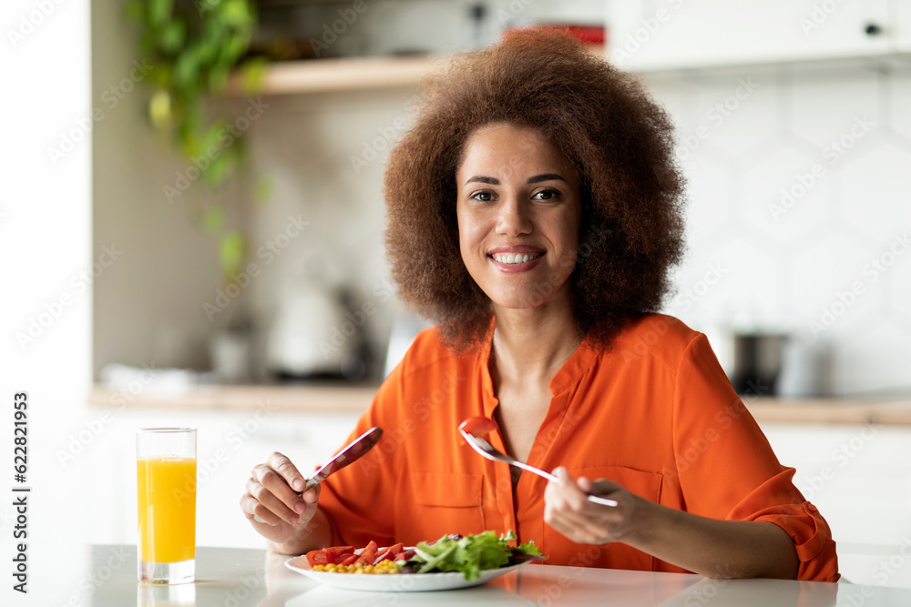 Smiling African American Lady Eating Breakfast Or Lunch At Table In Kitchen Smiling African American Lady Eating Breakfast Or Lunch At Table In Kitchen