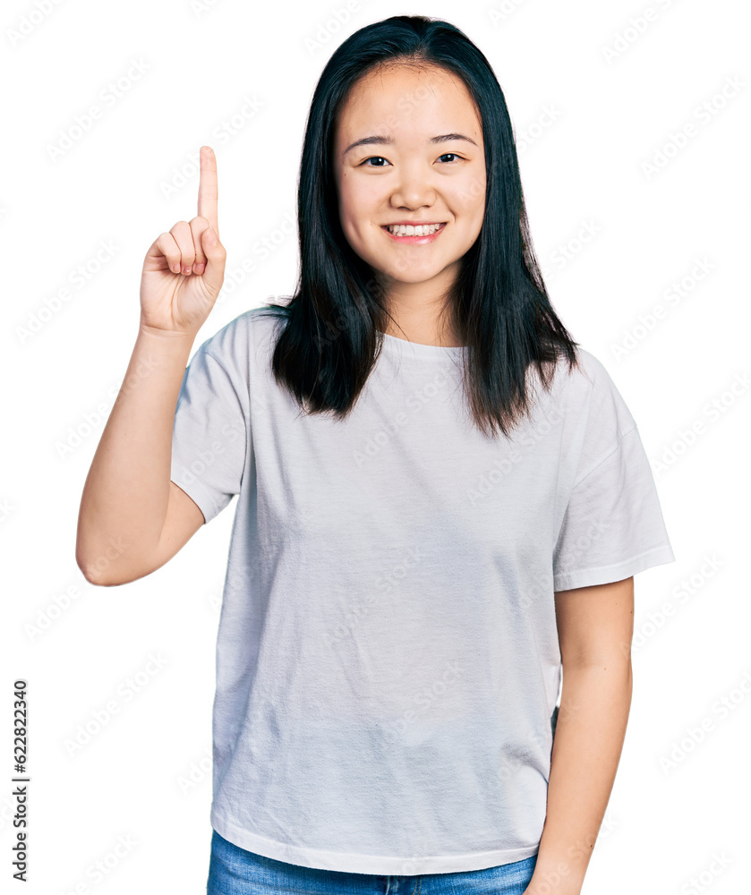 Young chinese woman wearing casual white t shirt showing and pointing up with finger number one while smiling confident and happy. Young chinese woman wearing casual white t shirt showing and pointing up with finger number one while smiling confident and happy.