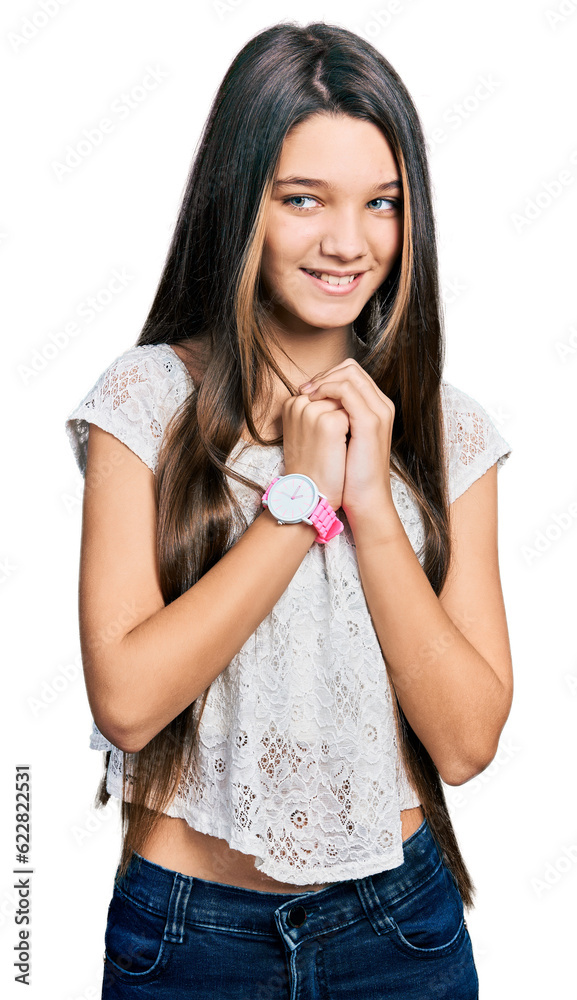 Young brunette girl with long hair wearing white shirt laughing nervous and excited with hands on chin looking to the side