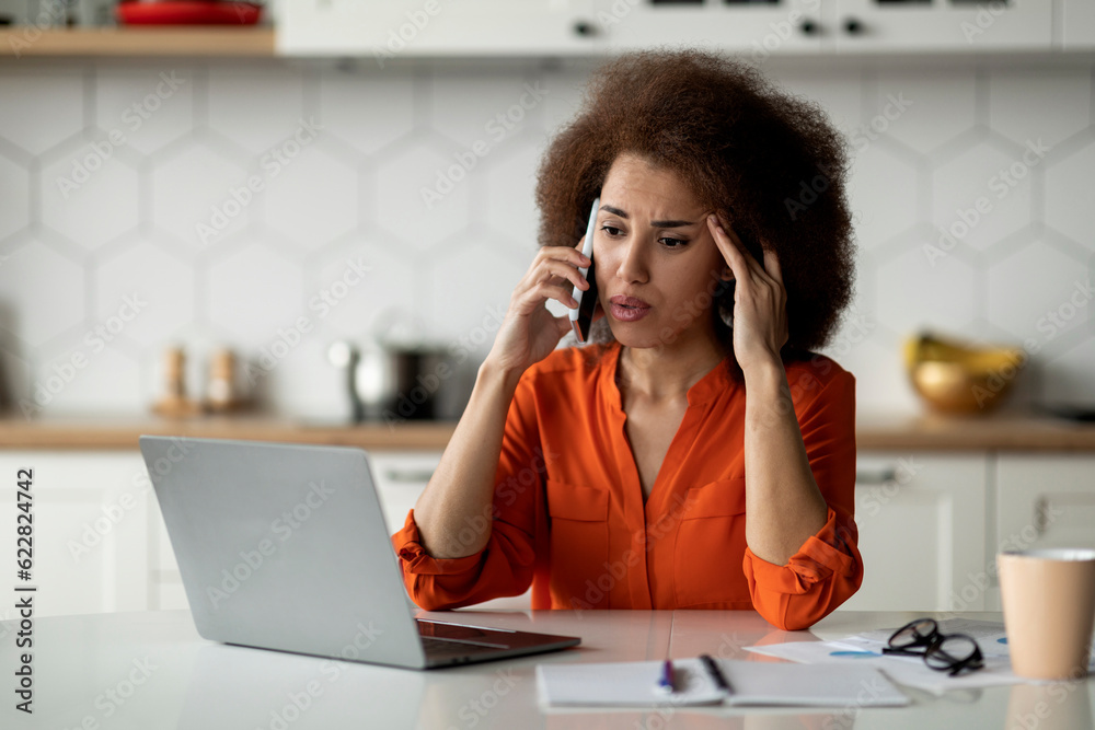 Obraz premium Bad News. Stressed Black Woman Looking At Laptop And Talking On Cellphone