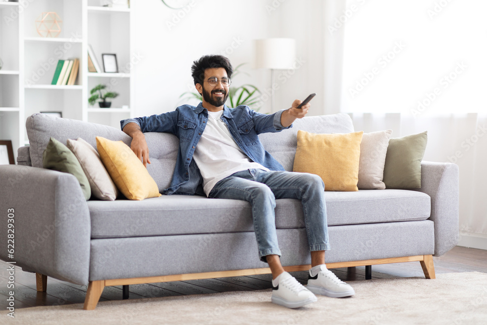 Portrait Of Happy Young Indian Guy Watching TV On Couch At Home Portrait Of Happy Young Indian Guy Watching TV On Couch At Home