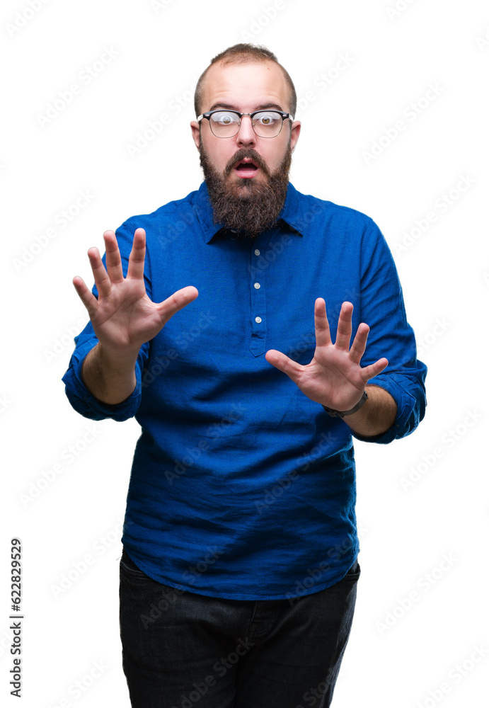 Young caucasian hipster man wearing glasses over isolated background afraid and terrified with fear expression stop gesture with hands, shouting in shock. Panic concept. Young caucasian hipster man wearing glasses over isolated background afraid and terrified with fear expression stop gesture with hands, shouting in shock. Panic concept.
