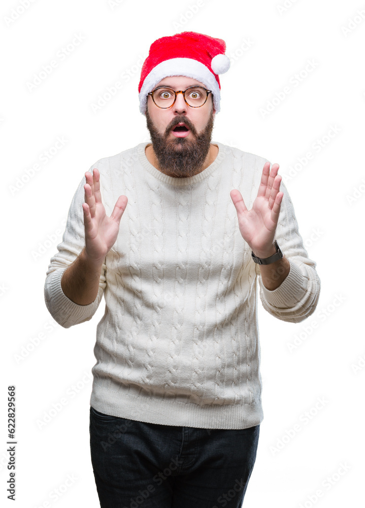 Young caucasian man wearing christmas hat and glasses over isolated background afraid and shocked with surprise expression, fear and excited face. Young caucasian man wearing christmas hat and glasses over isolated background afraid and shocked with surprise expression, fear and excited face.