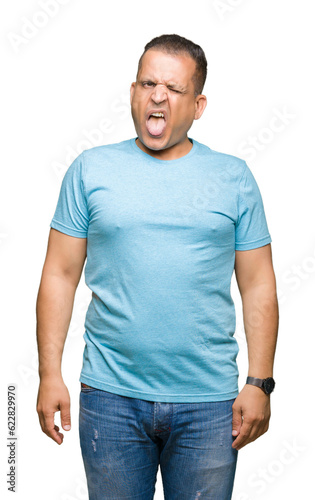 Middle age arab man wearing blue t-shirt over isolated background sticking tongue out happy with funny expression. Emotion concept.