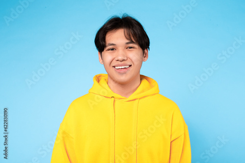 Portrait Of Young Smiling Asian Guy Posing Over Blue Background