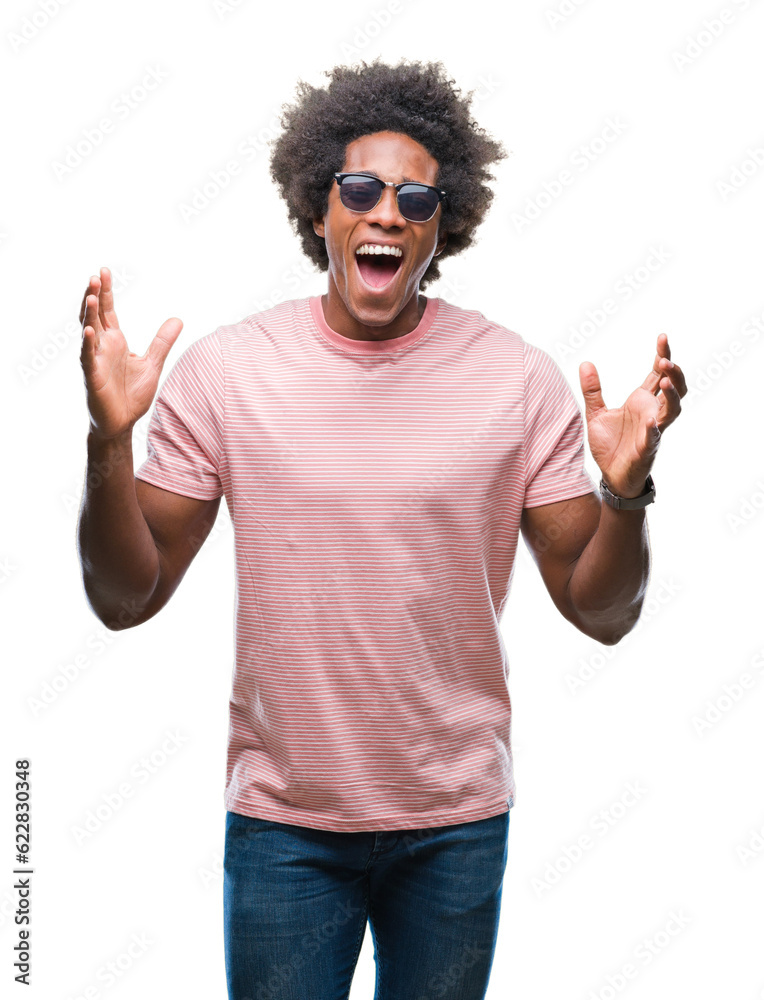 Afro american man wearing sunglasses over isolated background celebrating mad and crazy for success with arms raised and closed eyes screaming excited. Winner concept Afro american man wearing sunglasses over isolated background celebrating mad and crazy for success with arms raised and closed eyes screaming excited. Winner concept