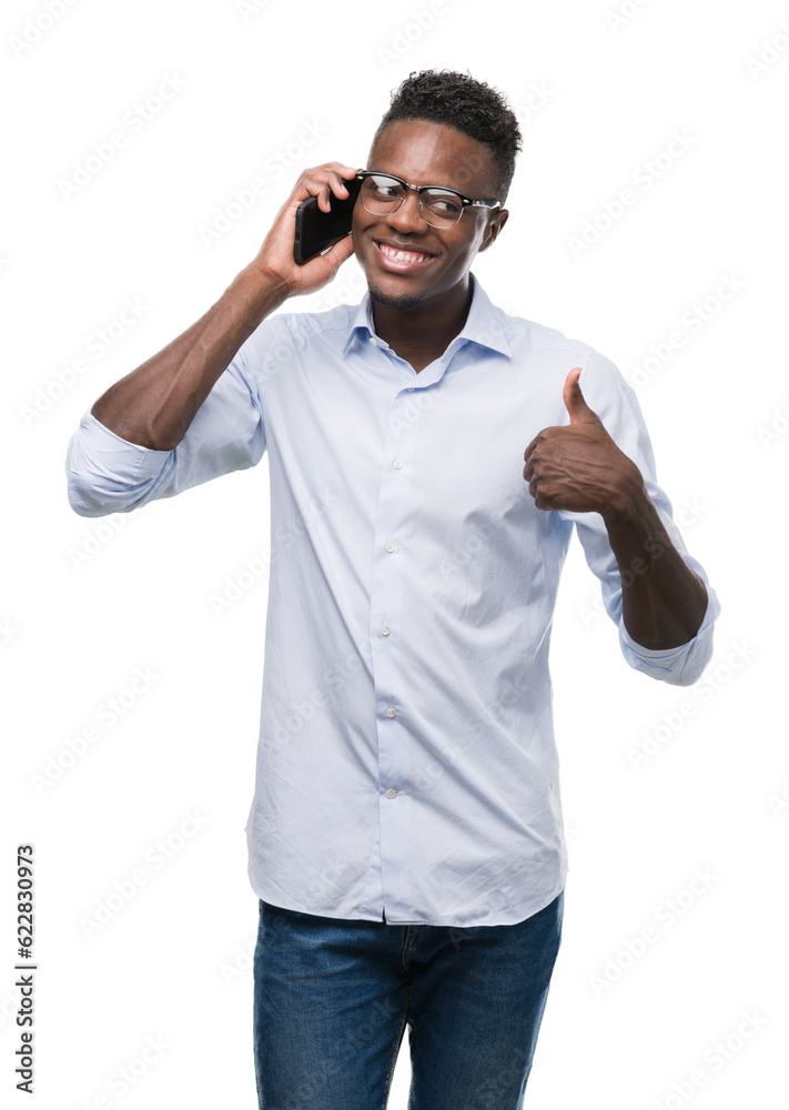 Fototapeta premium Young african american man using smartphone happy with big smile doing ok sign, thumb up with fingers, excellent sign