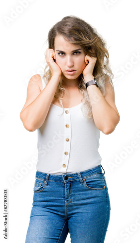 Young beautiful blonde woman over isolated background covering ears with fingers with annoyed expression for the noise of loud music. Deaf concept.