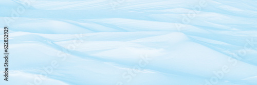 Wide panoramic winter background with snowy ground. Natural snow texture. Wind sculpted patterns on snow surface. © Andrei Stepanov