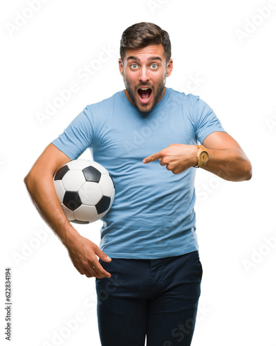 Young handsome man holding soccer football ball over isolated background very happy pointing with hand and finger