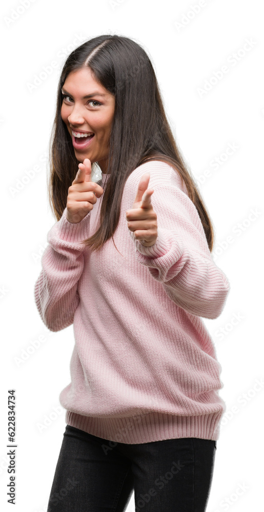 Young beautiful hispanic woman wearing a sweater pointing fingers to camera with happy and funny face. Good energy and vibes. Young beautiful hispanic woman wearing a sweater pointing fingers to camera with happy and funny face. Good energy and vibes.