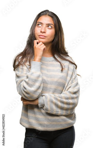 Young beautiful arab woman wearing winter sweater over isolated background with hand on chin thinking about question, pensive expression. Smiling with thoughtful face. Doubt concept. photo