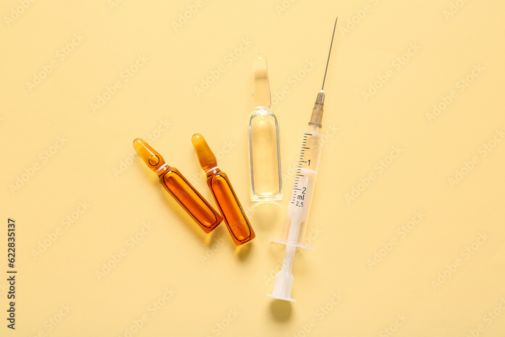 Ampules with syringe on light yellow background