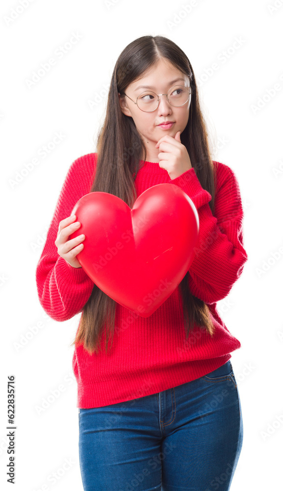 Young Chinese woman wearing graduate uniform red heart serious face thinking about question, very confused idea Young Chinese woman wearing graduate uniform red heart serious face thinking about question, very confused idea