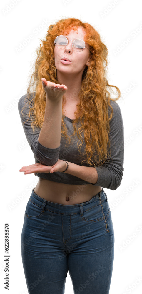 Young redhead woman looking at the camera blowing a kiss with hand on air being lovely and sexy. Love expression.