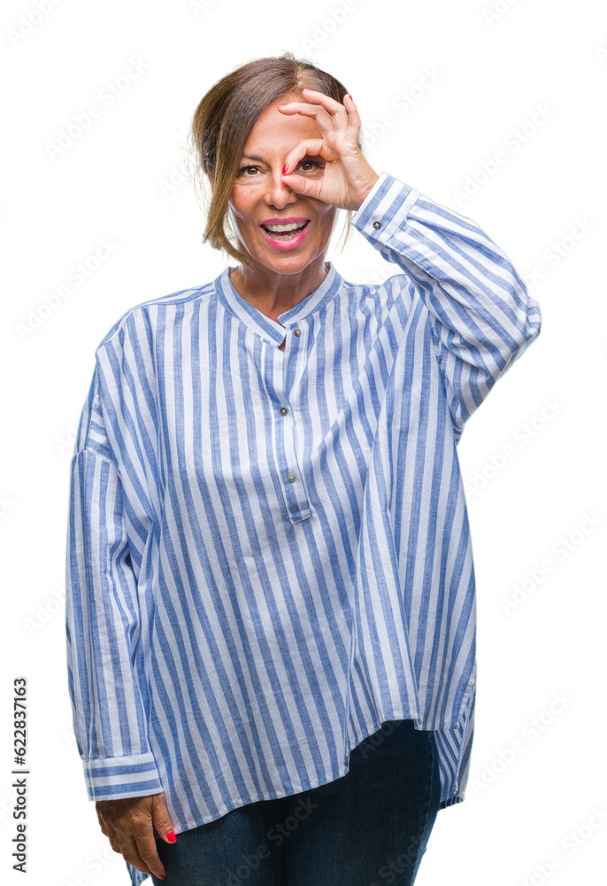 Middle age senior hispanic woman over isolated background doing ok gesture with hand smiling, eye looking through fingers with happy face. Middle age senior hispanic woman over isolated background doing ok gesture with hand smiling, eye looking through fingers with happy face.