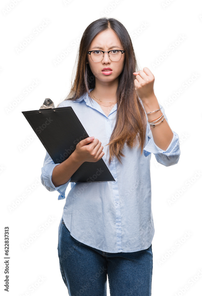Young asian business woman holding clipboard over isolated background annoyed and frustrated shouting with anger, crazy and yelling with raised hand, anger concept Young asian business woman holding clipboard over isolated background annoyed and frustrated shouting with anger, crazy and yelling with raised hand, anger concept