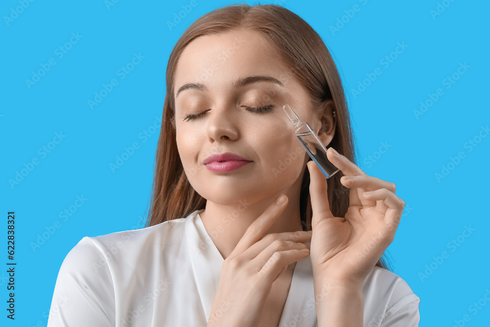 Beautiful young woman with ampule on blue background. Skin care concept Beautiful young woman with ampule on blue background. Skin care concept