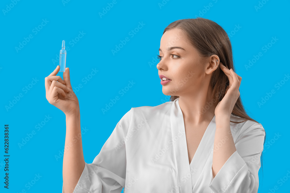Beautiful young woman with ampule on blue background. Skin care concept Beautiful young woman with ampule on blue background. Skin care concept