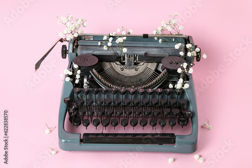 Vintage typewriter with gypsophila flowers on pink background